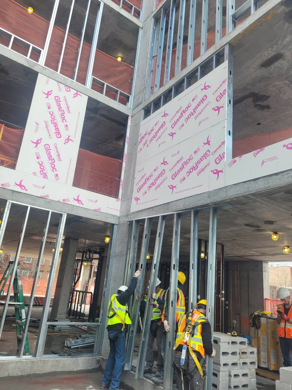 Crew installing light-gauge steel framing on a multi-story build