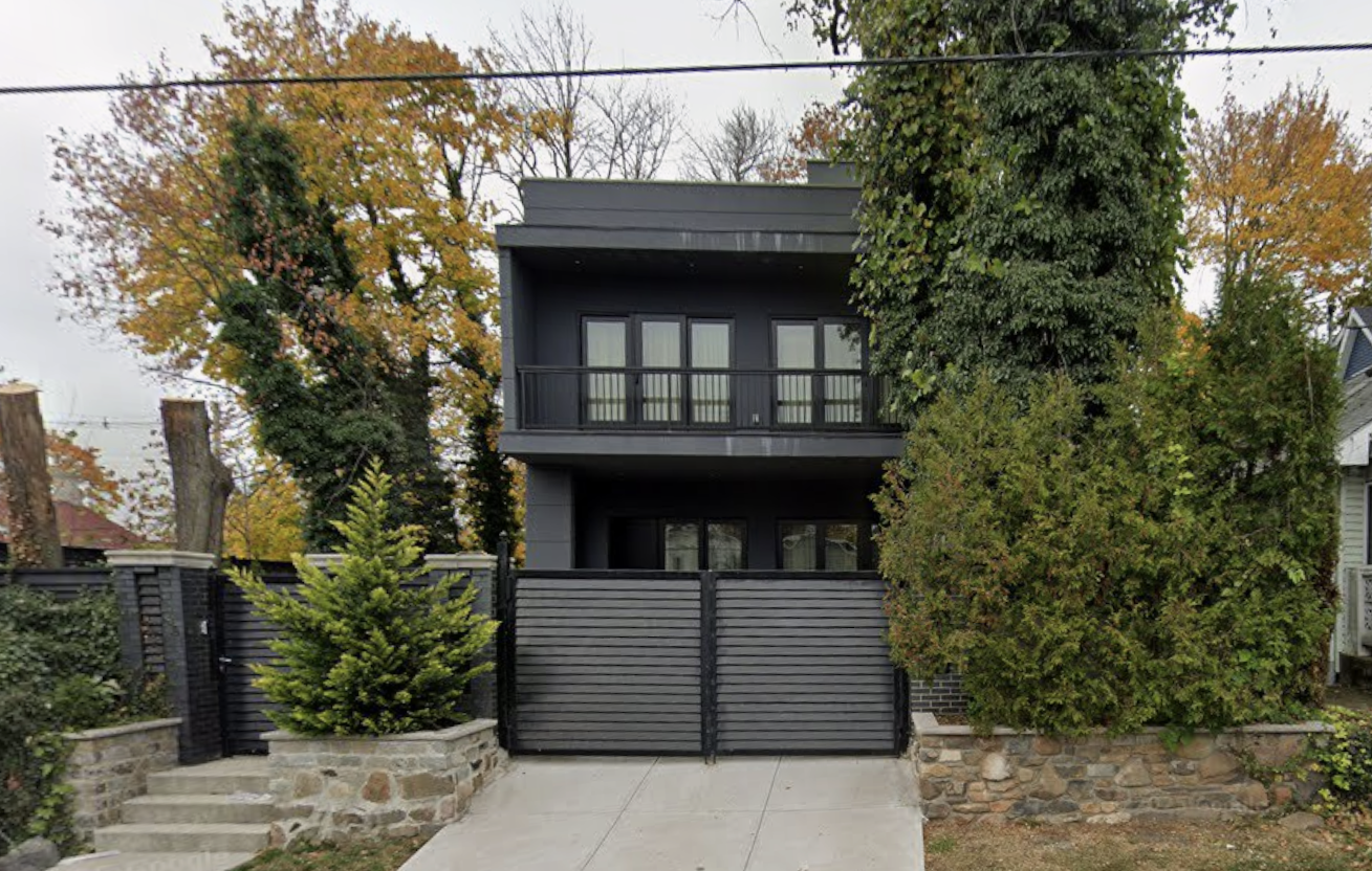 Custom black mansion with hand-laid stone perimeter wall by VIK MGM