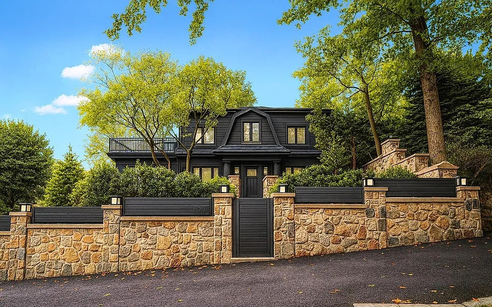 Black gambrel residence behind hand-laid stone perimeter