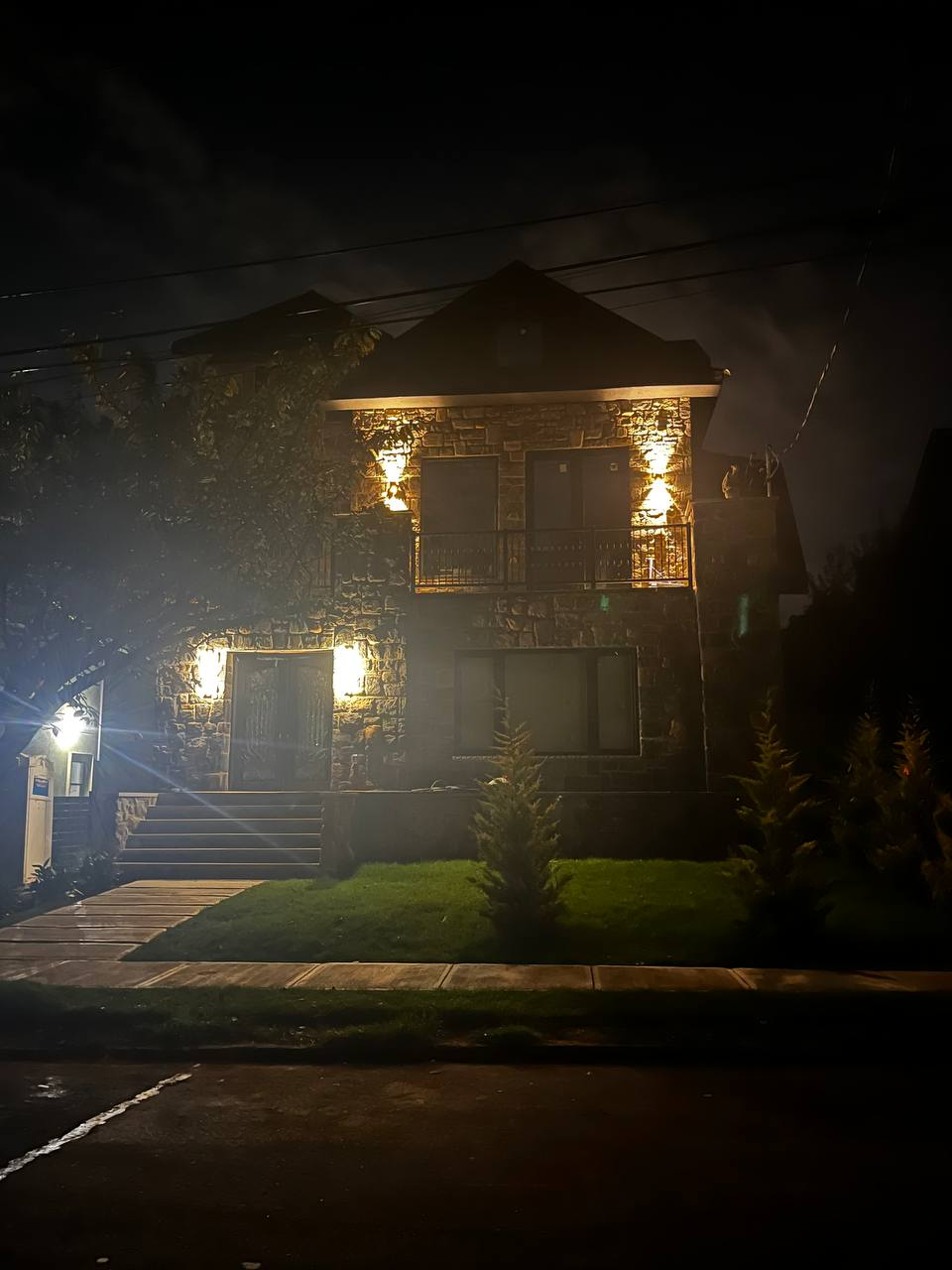 Same VIK MGM stone residence at night, exterior lighting on